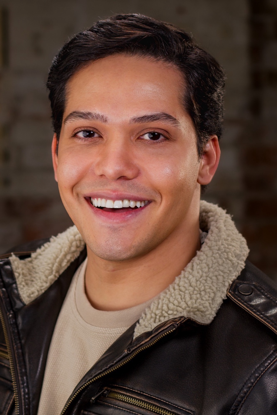 Bruno DiSanto, headshot smiling, in a leather jacket with a shearling collar